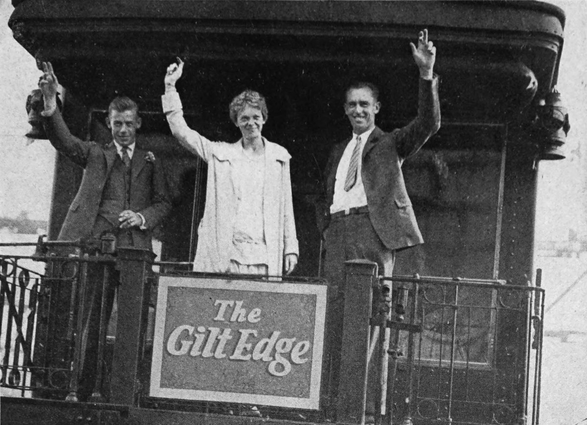 Photo wide outdoor shot of Friendship waving from rear platform rail car; a sign saying “The Gilt Edge”
                hangs on railing