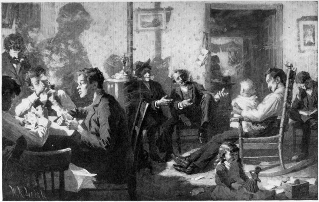 A room full of mostly men chatting.
One man is sitting in a rocking chair holding a toddler.