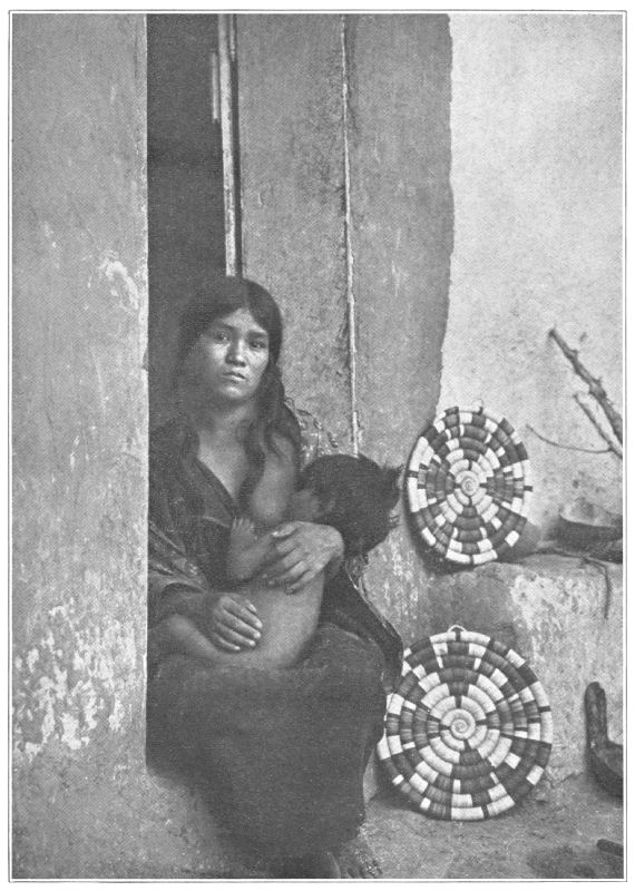 A Hopi woman and child sit in a doorway